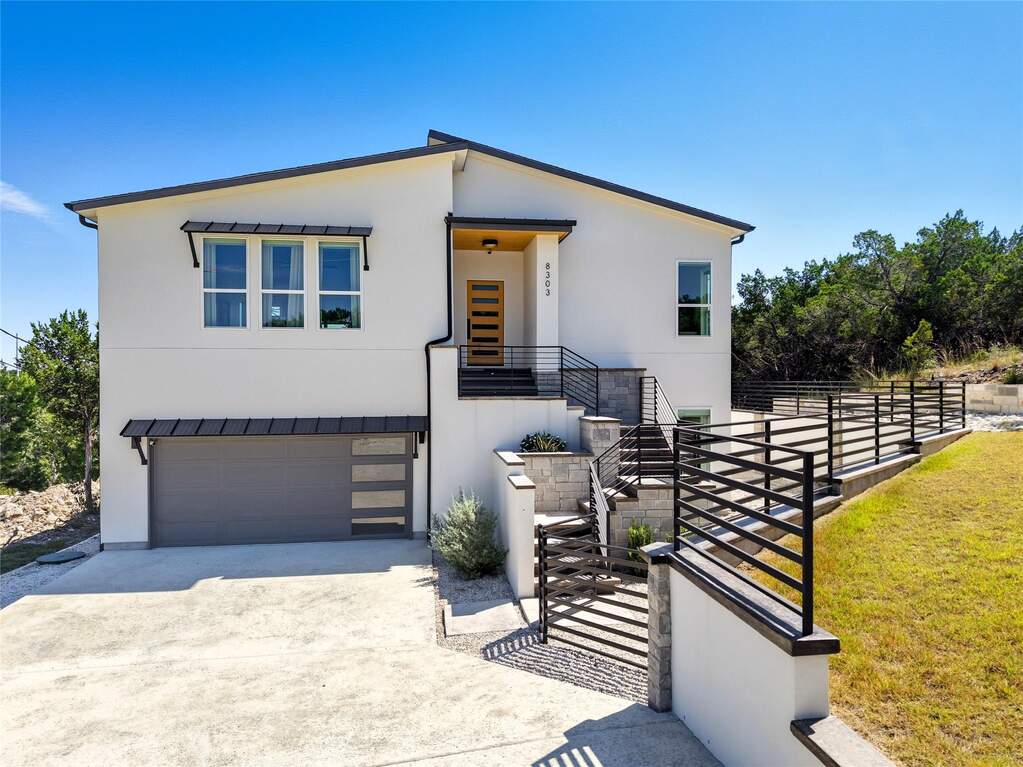 Modern home with driveway, stucco siding, stairway, and an attached garage