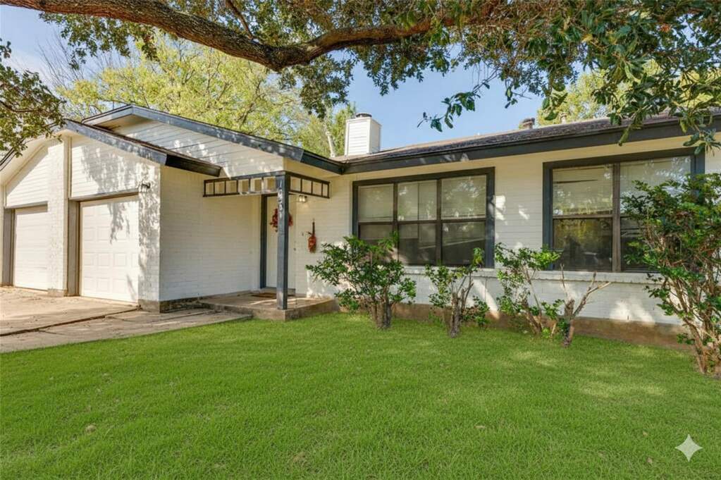 Ranch-style home with a front lawn, a chimney, a garage, and concrete driveway