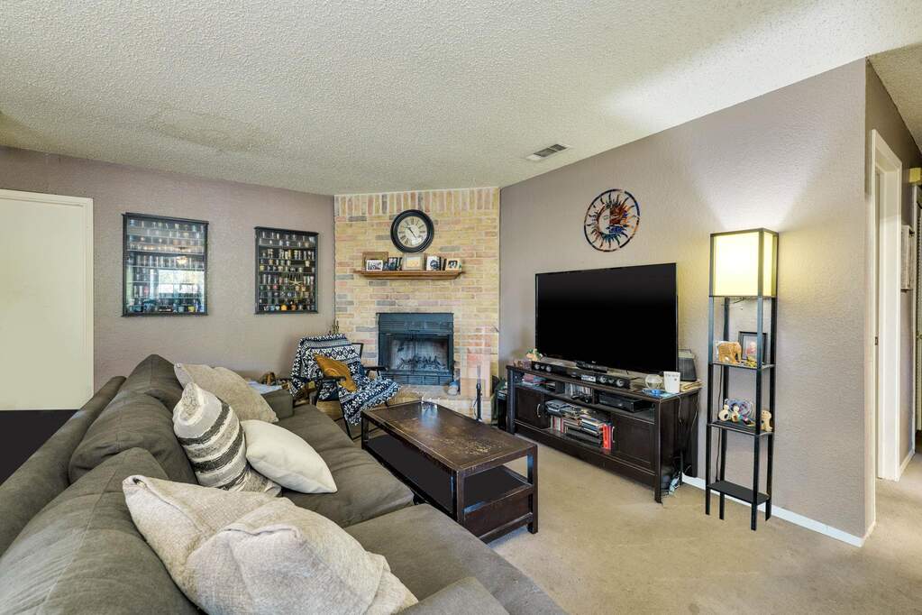 Living area featuring light carpet, a textured ceiling, a fireplace, and a textured wall