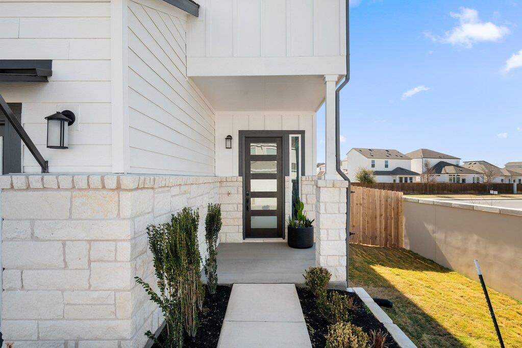 Modern exterior featuring white horizontal siding, a stone veneer foundation, and a covered entryway