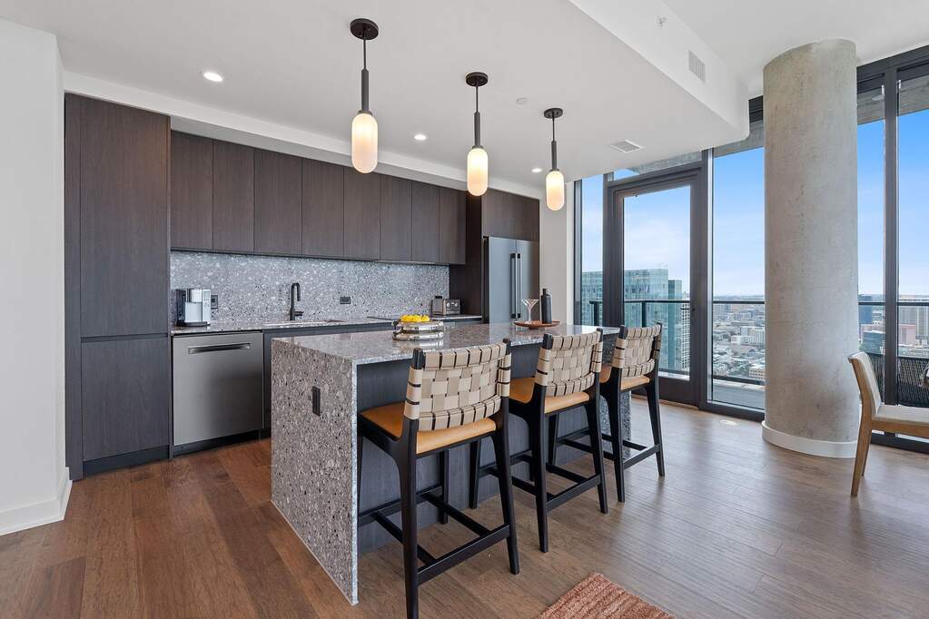 Representative Photo. Kitchen featuring custom Italkraft cabninetry, terrazzo backsplash, waterfall-edge terrazzo countertops, black stainless steel Bosch appliances, and pendant lighting abo