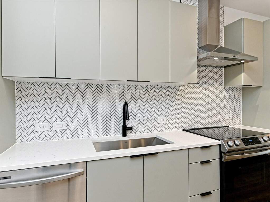 Kitchen with appliances with stainless steel finishes, wall chimney range hood, and gray cabinets