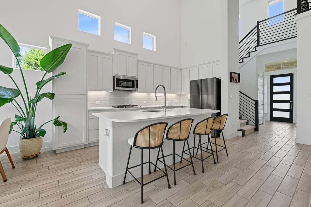 Kitchen with healthy amount of natural light, a kitchen breakfast bar, a towering ceiling, and wood tiled floors